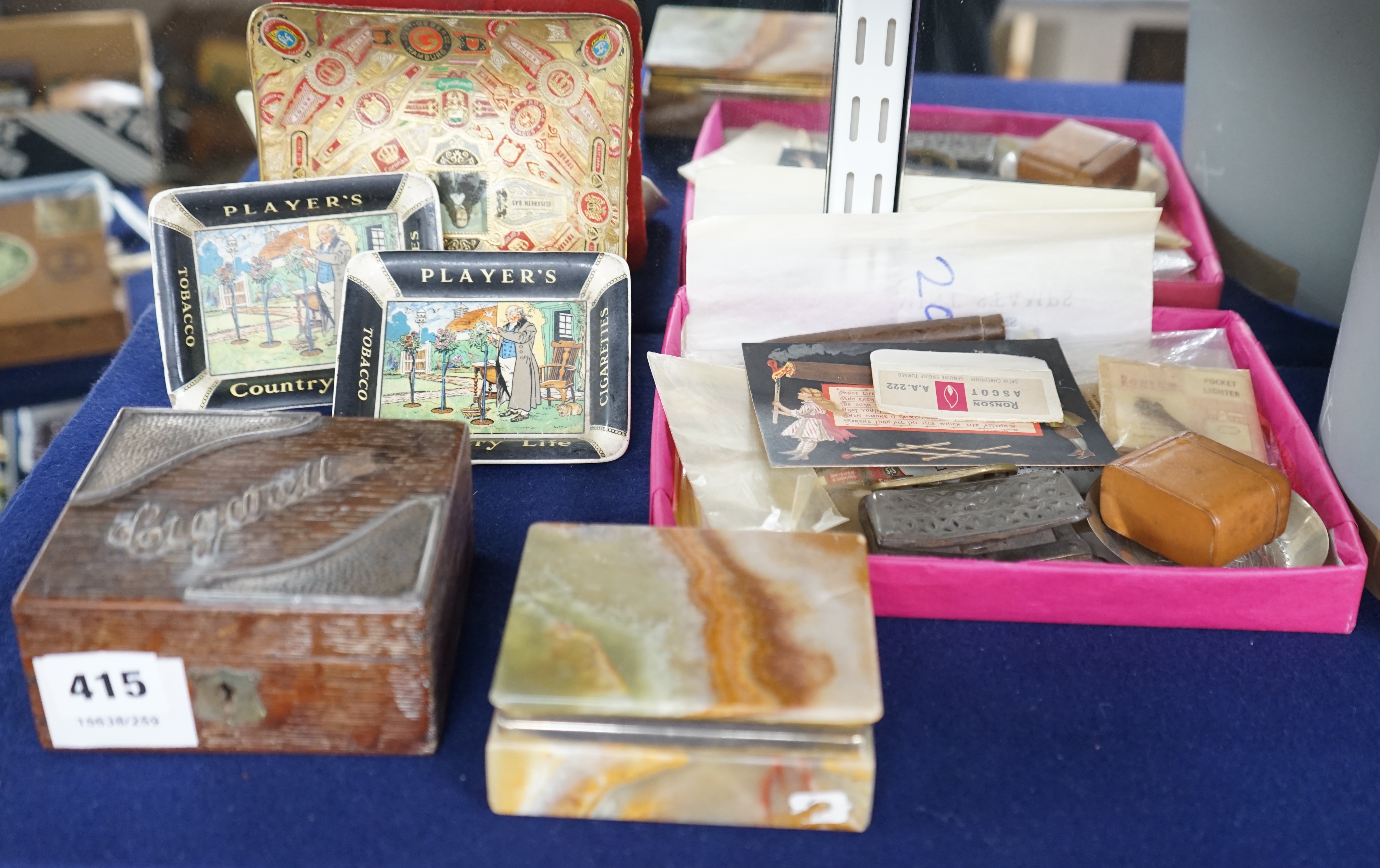 A collection of smoking accessories including an onyx cigarette box, an oak cigarette box, two Player’s ashtrays, a match box, cigarette box wrappers, etc. Condition - fair